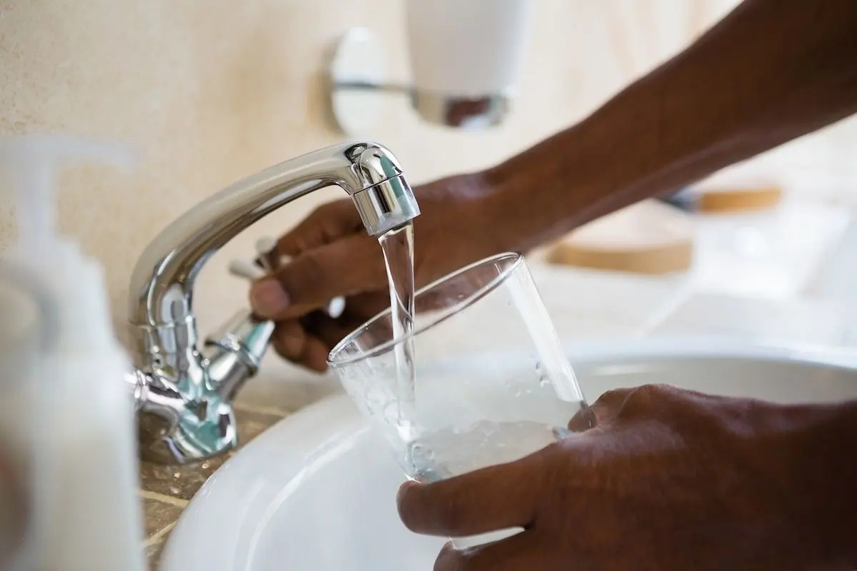 Closeup of a person getting a glass of tap water from a sink