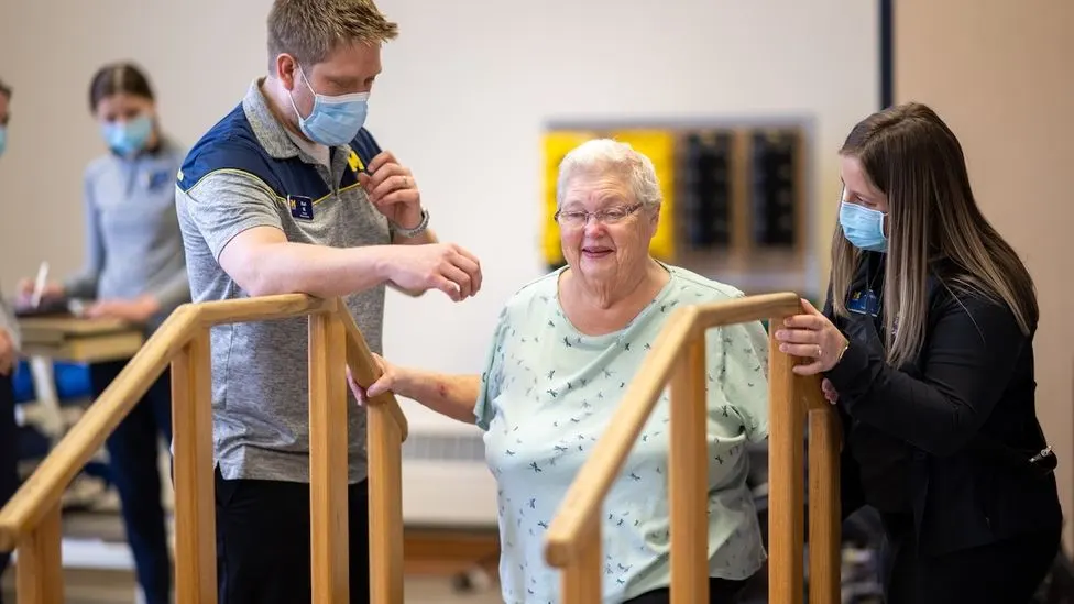 Students helping a clinic patient practice using stairs