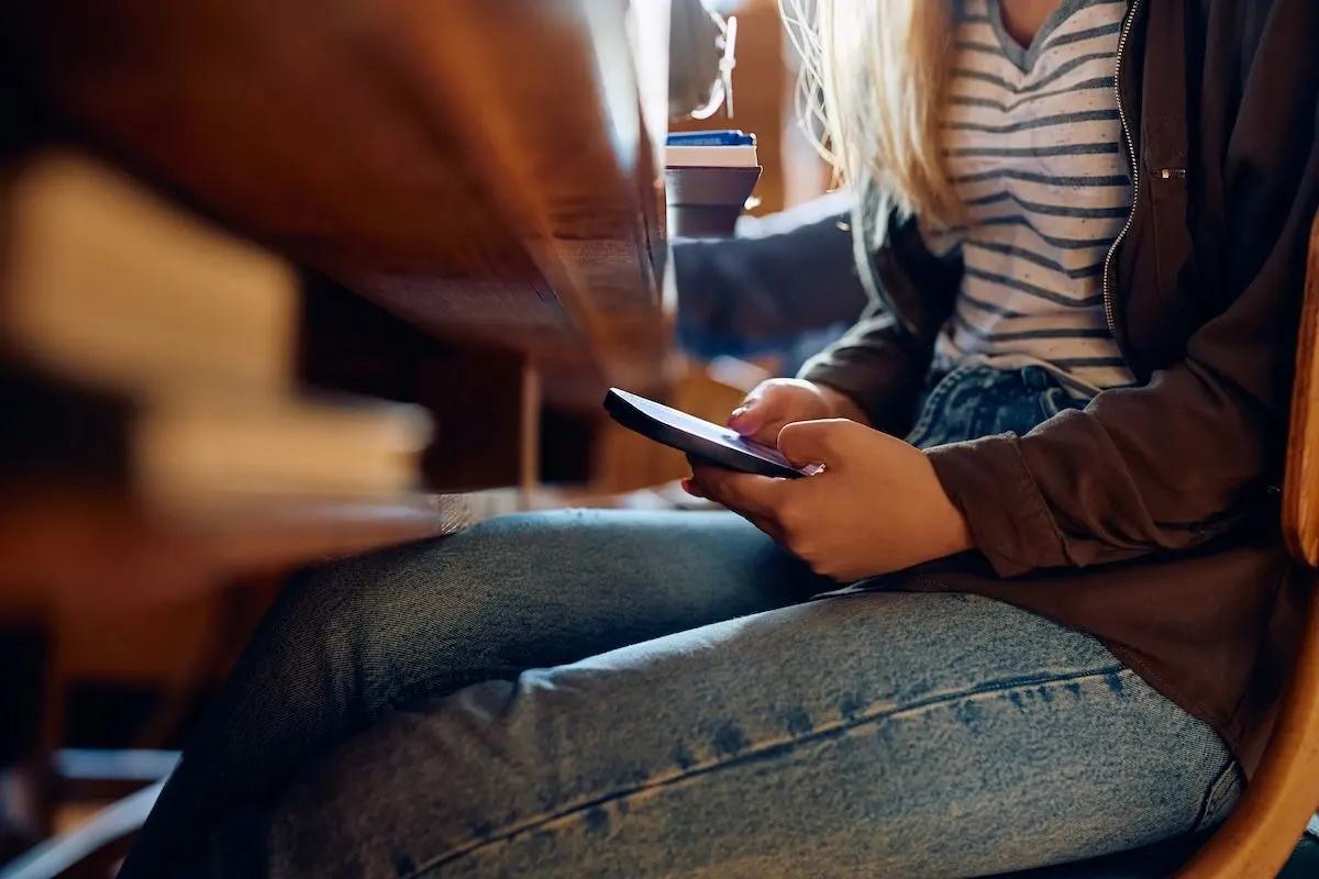 A student looking at her phone under her desk