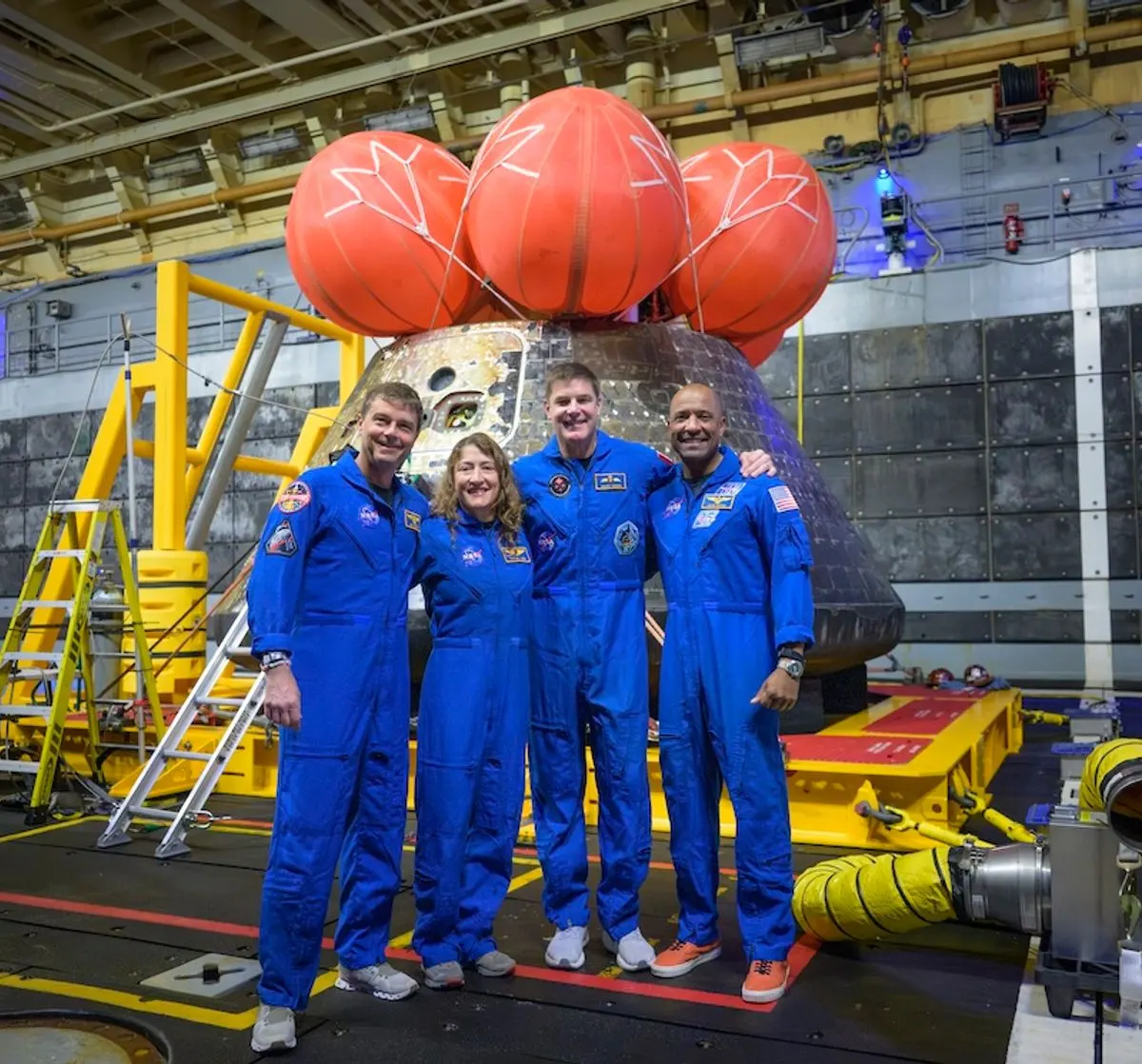 crew members of the Artemis II mission posing with their Orion spacecraft capsule