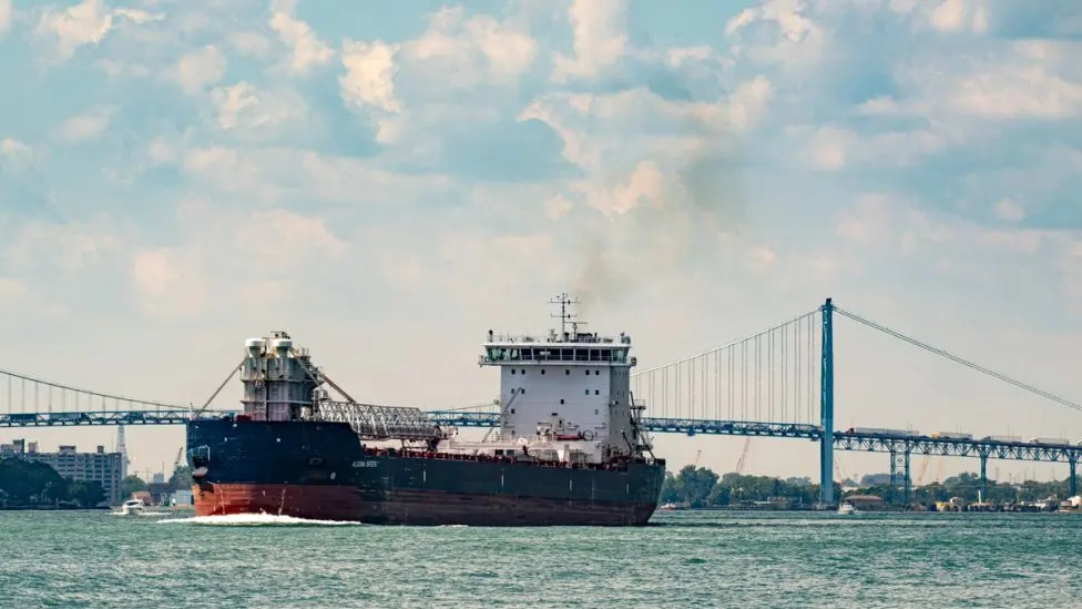 A shipping vessel passing in front of the Ambassador Bridge in Detroit