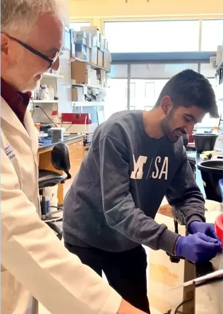 Henry Paulson and a researcher work at a laboratory bench