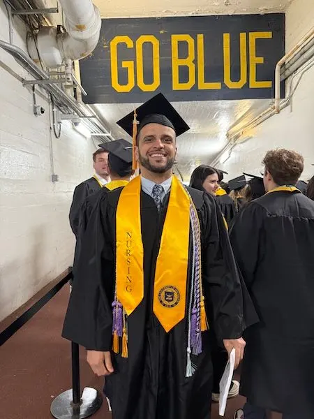 Joshua Truchan wearing a graduation cap and gown in the Big House tunnel