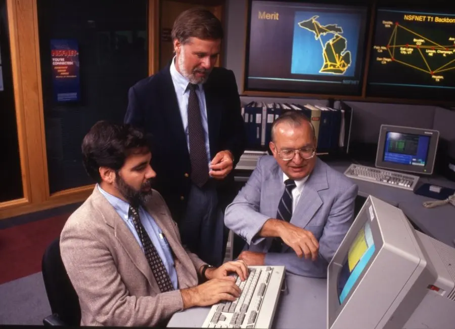 A vintage photo of men working on a personal computer (PC)