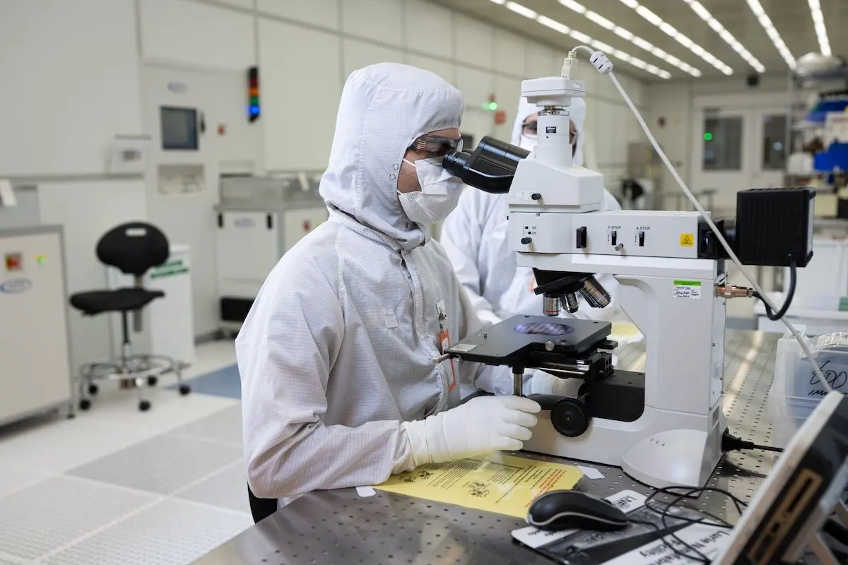 an engineer inspecting a semiconductor wafer under a microscope inside the Lurie Nanofabrication Facility (LNF)