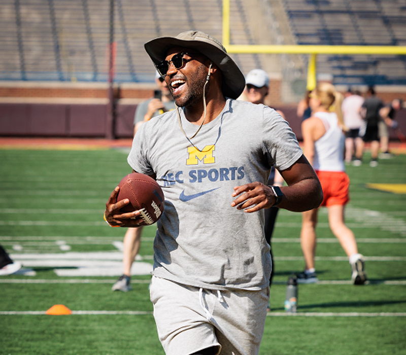 A man runs with a football cradled in his right arm