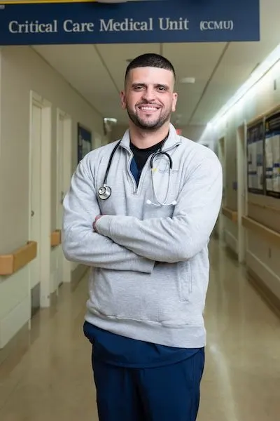 Joshua Truchan stands in the hallway of a hospital's Critical Care Medical Unit
