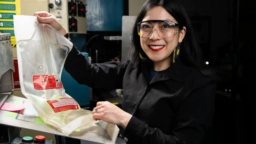 Grace Hsia Haberl wearing safety glasses and holding a bag of liquid