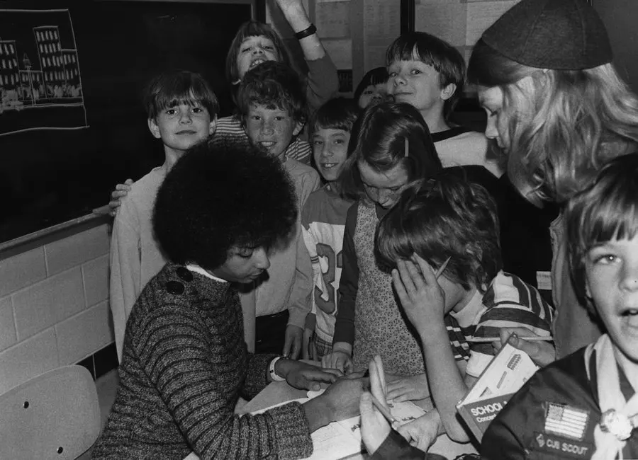 A black and white photo of a teacher working with elementary students in 1977