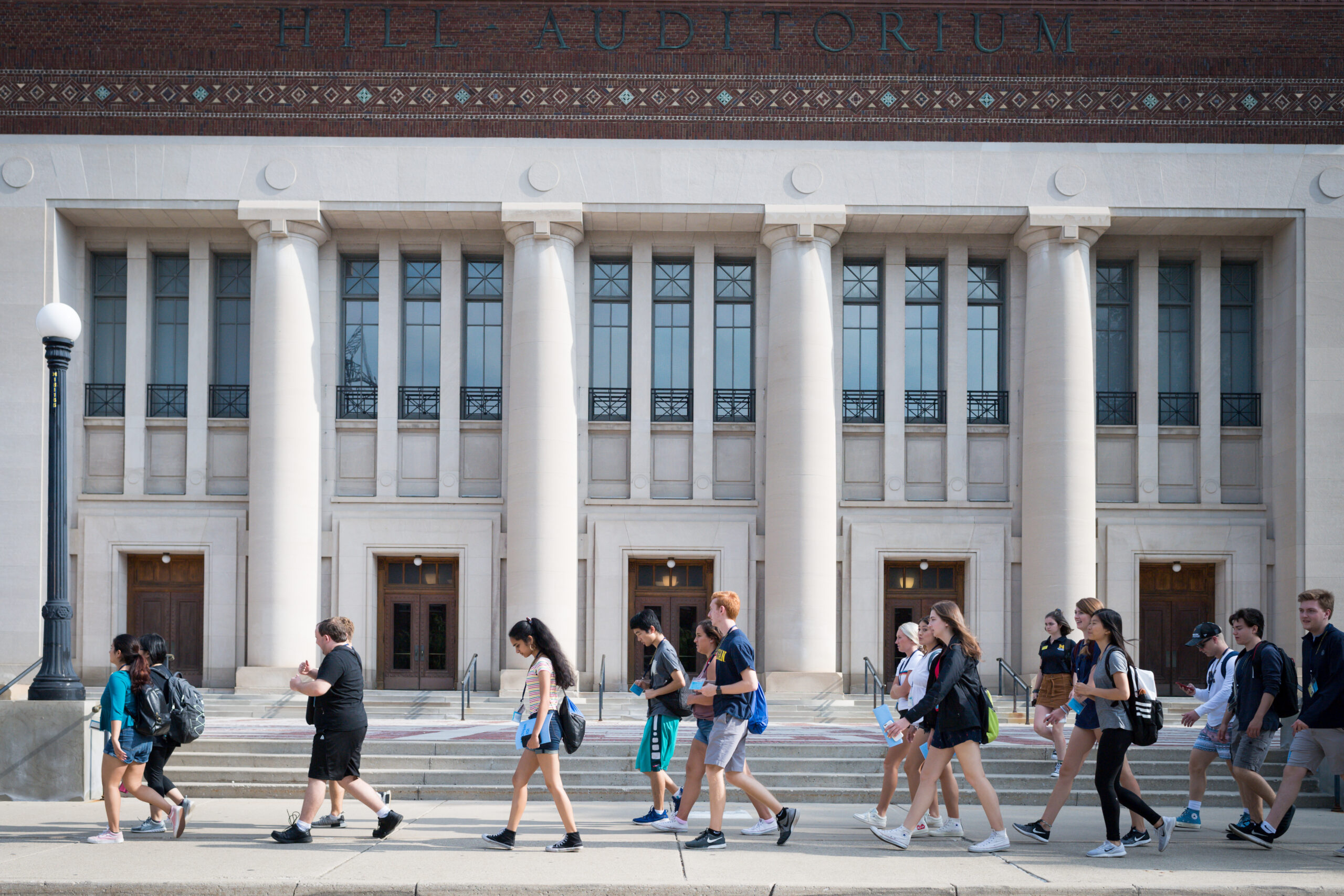 New students walk in group in front of campus building with large pillars