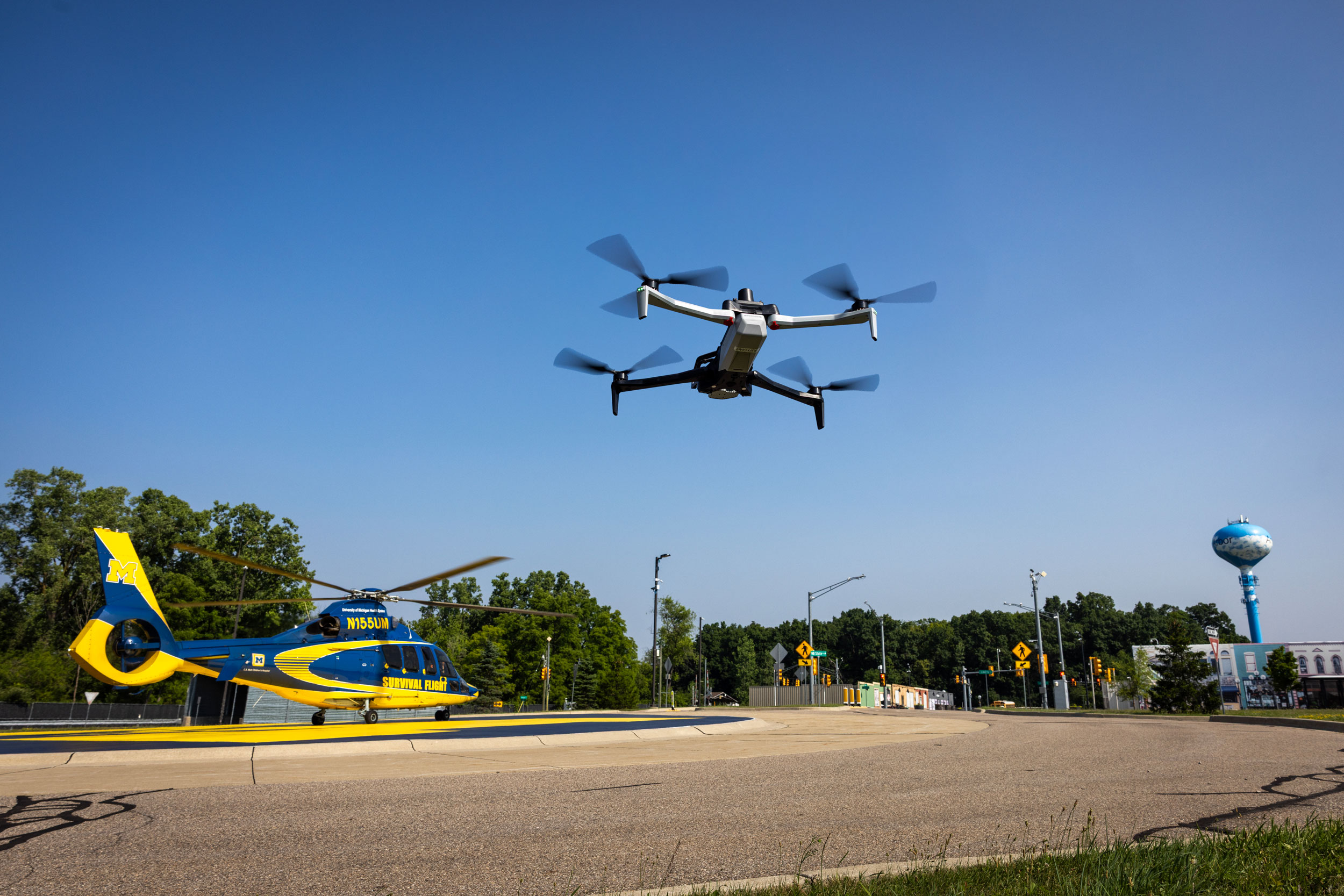 A drone flies in front of the U-M Survival Flight helicopter that landed on the block M road roundabout at Mcity on the University of Michigan’s North Campus.